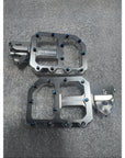 Pair of metallic bike pedals on a gray surface