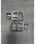 Pair of metallic bicycle pedals on a gray textured surface