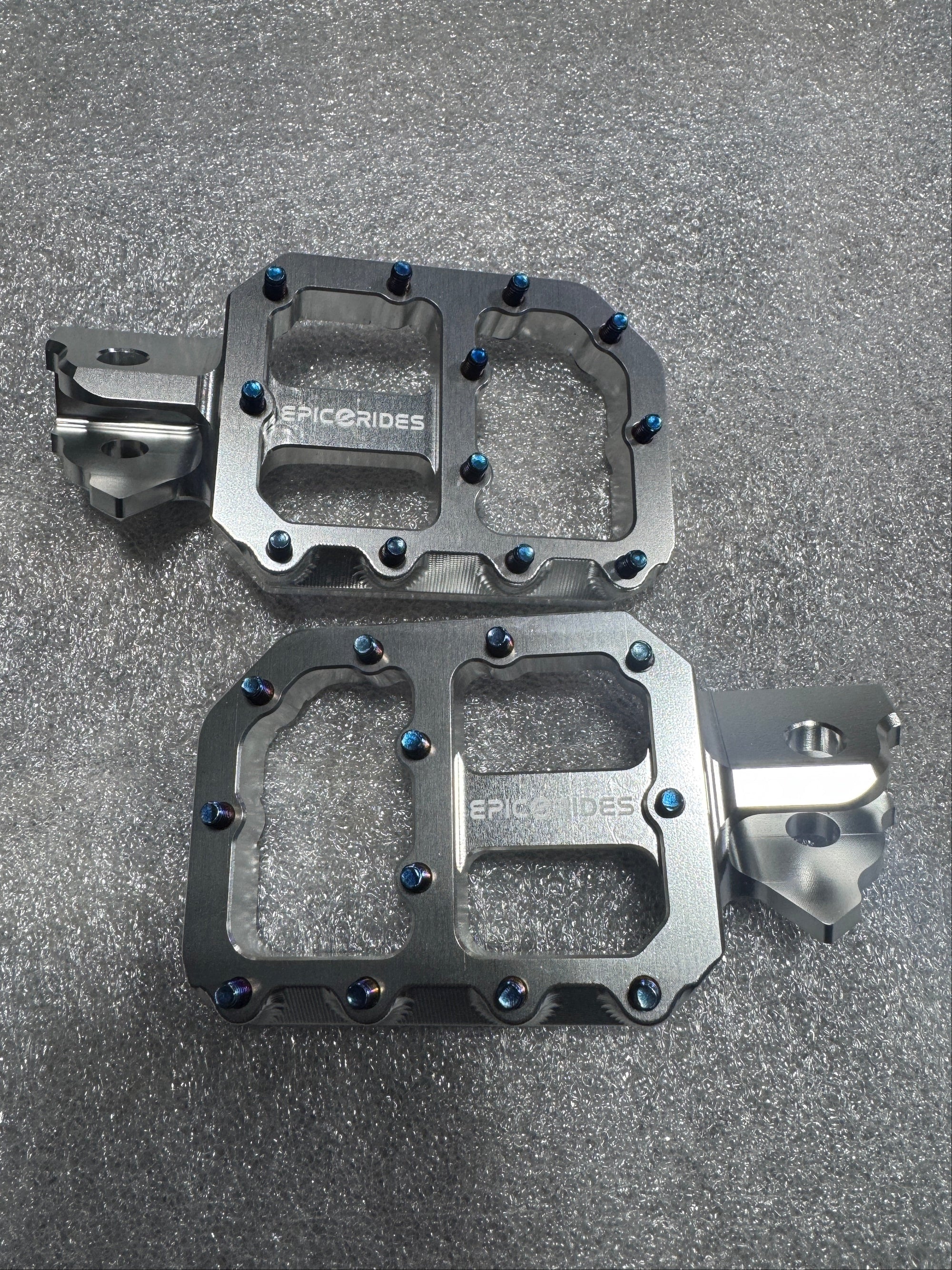 Pair of metallic bike pedals on a gray surface