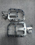 Pair of metallic bike pedals on a gray surface