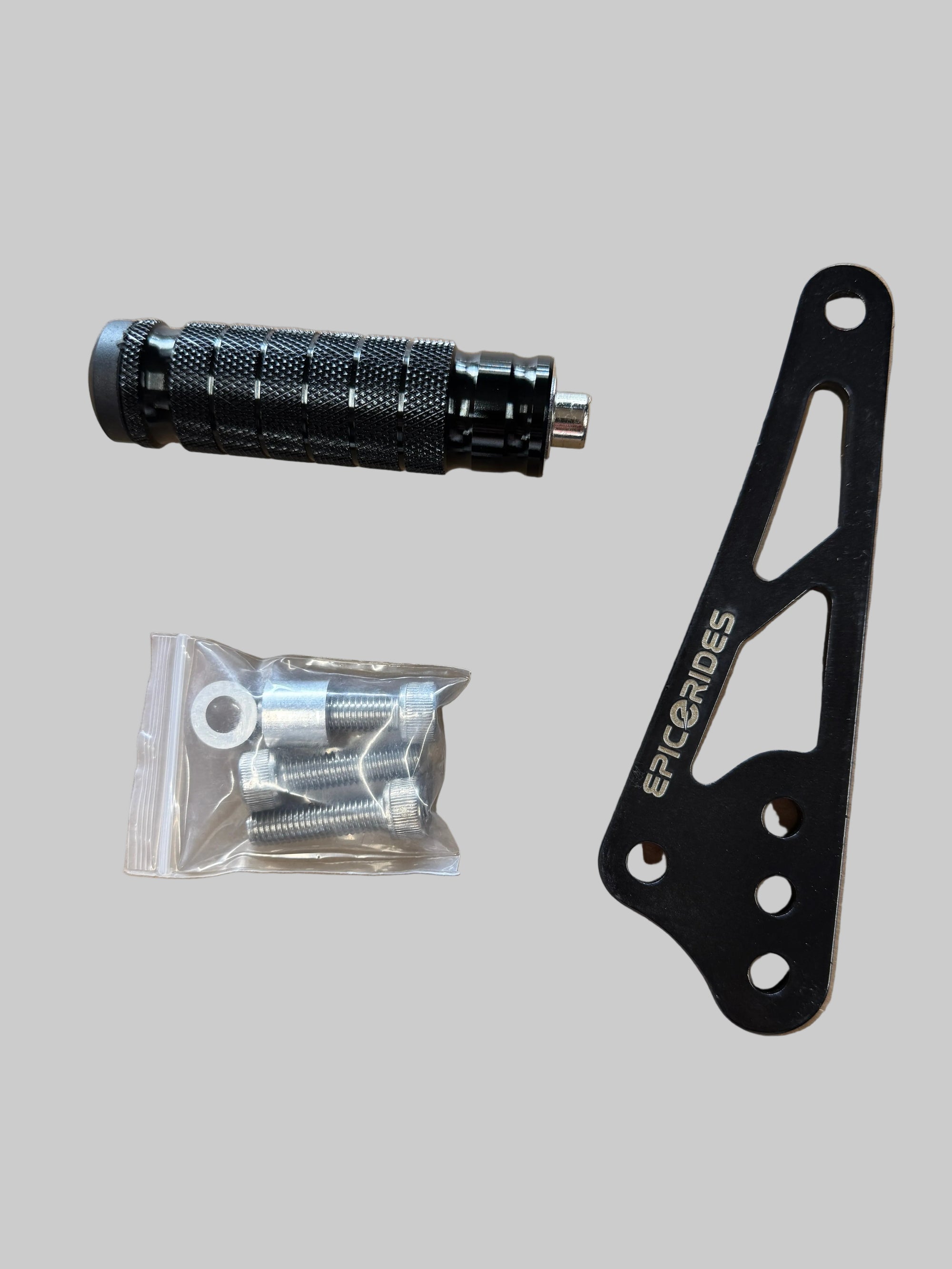 Black shift lock bracket with 'epic e rides' branding, a black foot lock, and a clear plastic bag with screws on a brown surface.