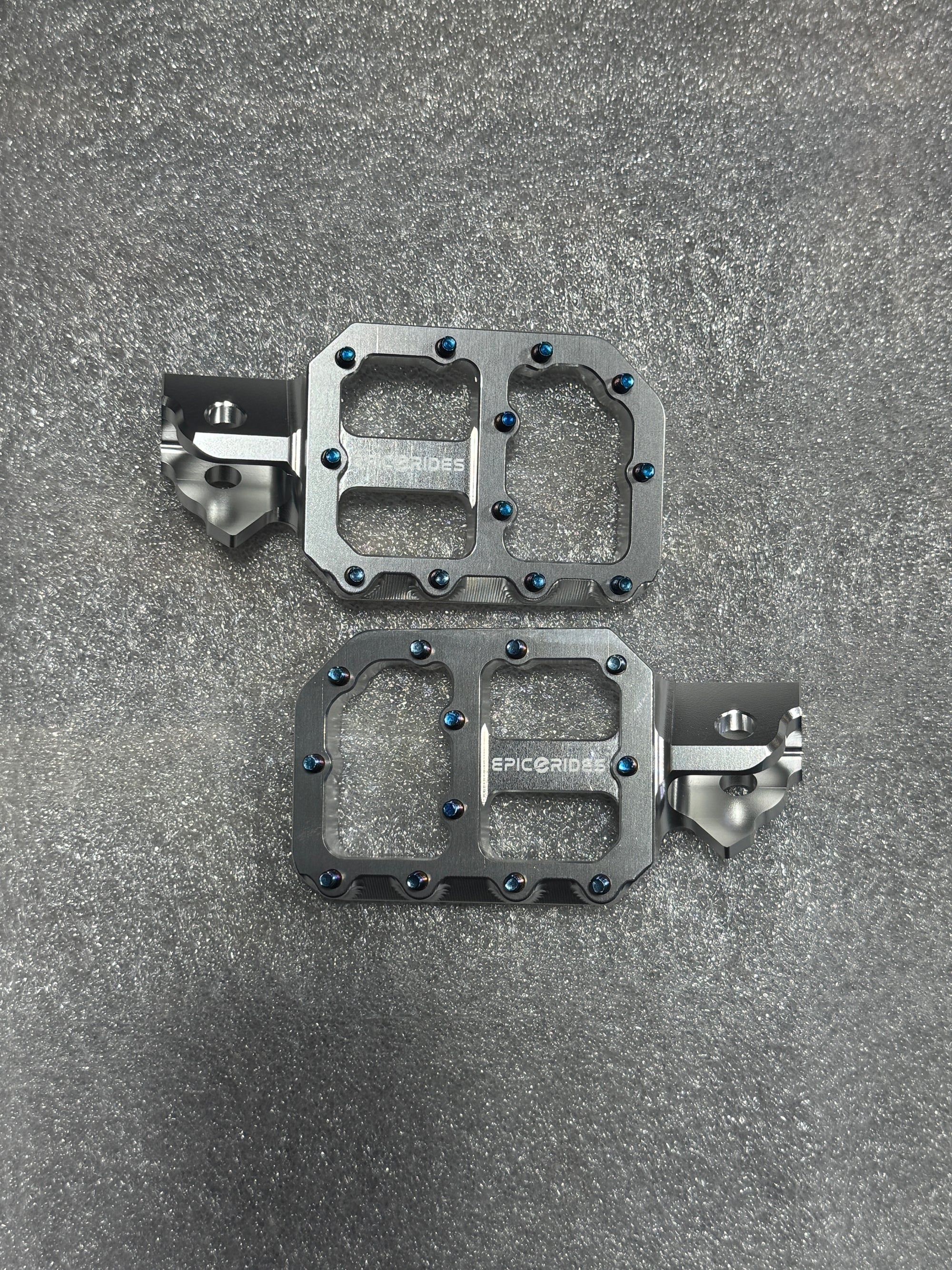 Pair of metallic bicycle pedals on a gray textured surface