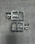 Pair of metallic bicycle pedals on a gray textured surface